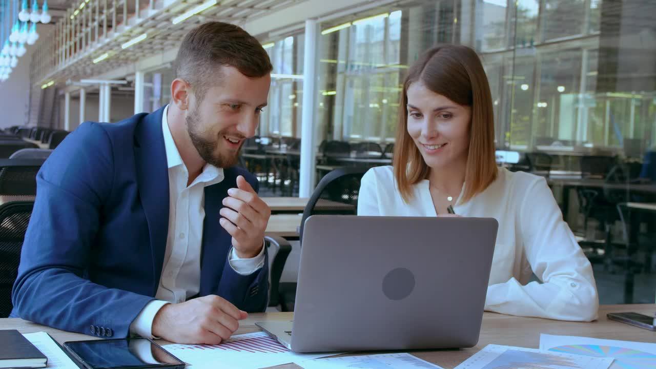 Two colleagues talking over a laptop in a bright office