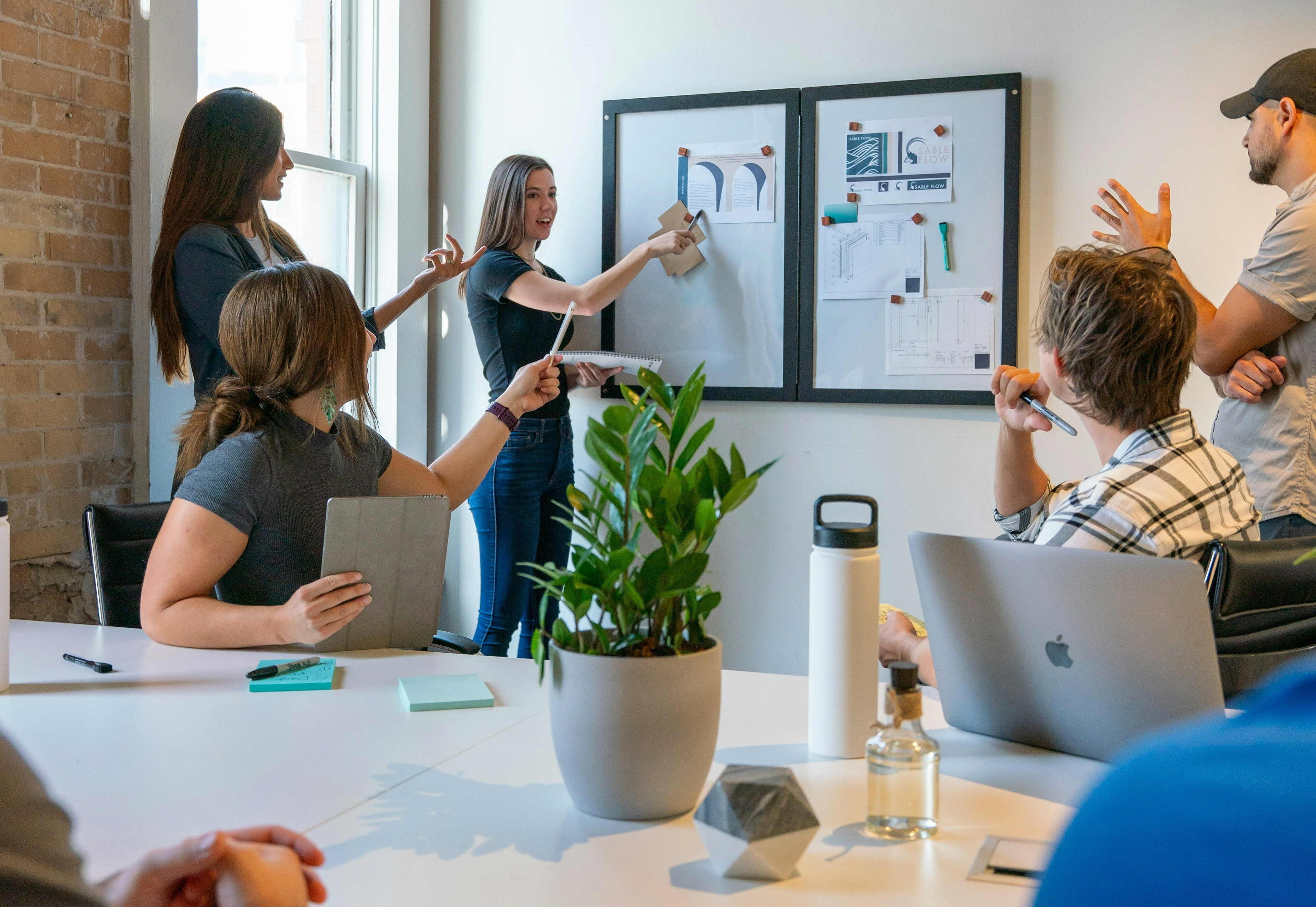 A team pinning design work to the wall during a bright studio working session